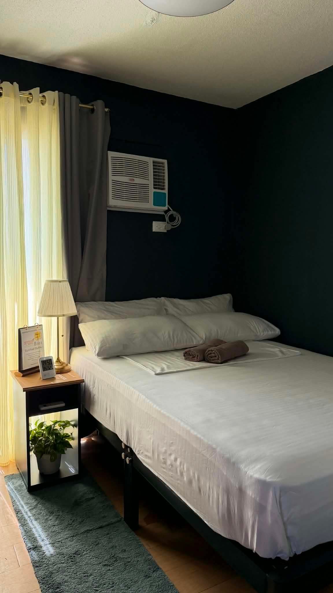 Tidy bedroom with fresh linens and a clean air-conditioning unit